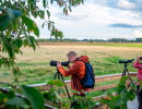 Two people standing with binoculars looking out over the landscape.