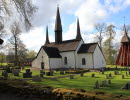 Kungslena kyrka. En vit stenkyrka med röd träklockstapel vid sidan.