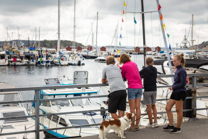 Familj står på strandpromenaden i centrala Strömstad och tittar ut över gästhamnen. 