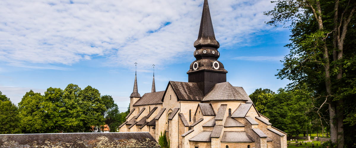 Varnhems klosterkyrka. I förgrunden syns vandrare gå mot den imponerande stenkyrkan.