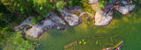 A wreck lying near land in the water. It can be seen from above.
