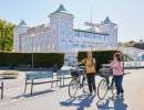 Två personer cyklar i en småstad.