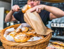 Caféägare lägger i nybakta bullar i en påse. 