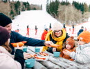 Familj tar en paus från skidåkning och äter en måltid.