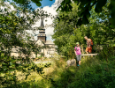 Man och kvinna som vandrar i gröngräset med Varnhems klosterkyrka i bakgrunden.