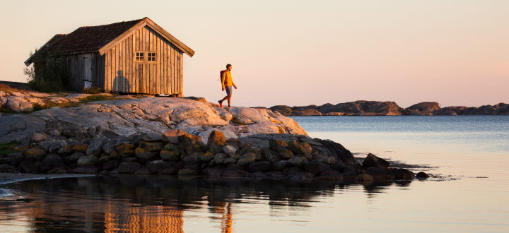 Vandrande man vid sjöbod i solnedgången