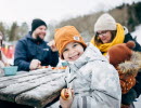 Familj tar en paus från skidåkning och äter en måltid.