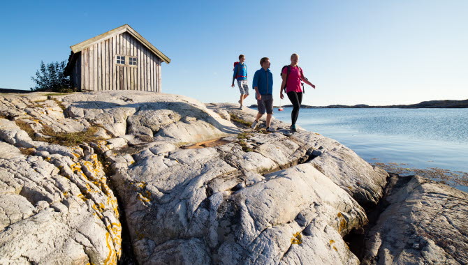 Sällskap vandrar på klipporna vid sjöbod