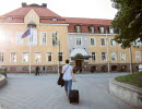 Woman walks towards hotel building.