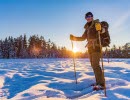 A beautiful sunny winter landscape. A person stands in the snow with skis on his feet and ski poles in their hands.