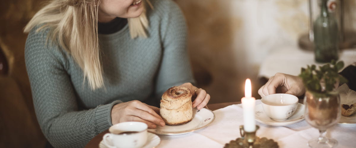 Kvinna fikar på kanelbulle och kaffe