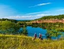 Two women are walking with their dogs and have just taken a break from a large quarry.