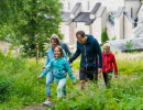 En familj ute i naturen, i bakgrunden en klosterkyrka.